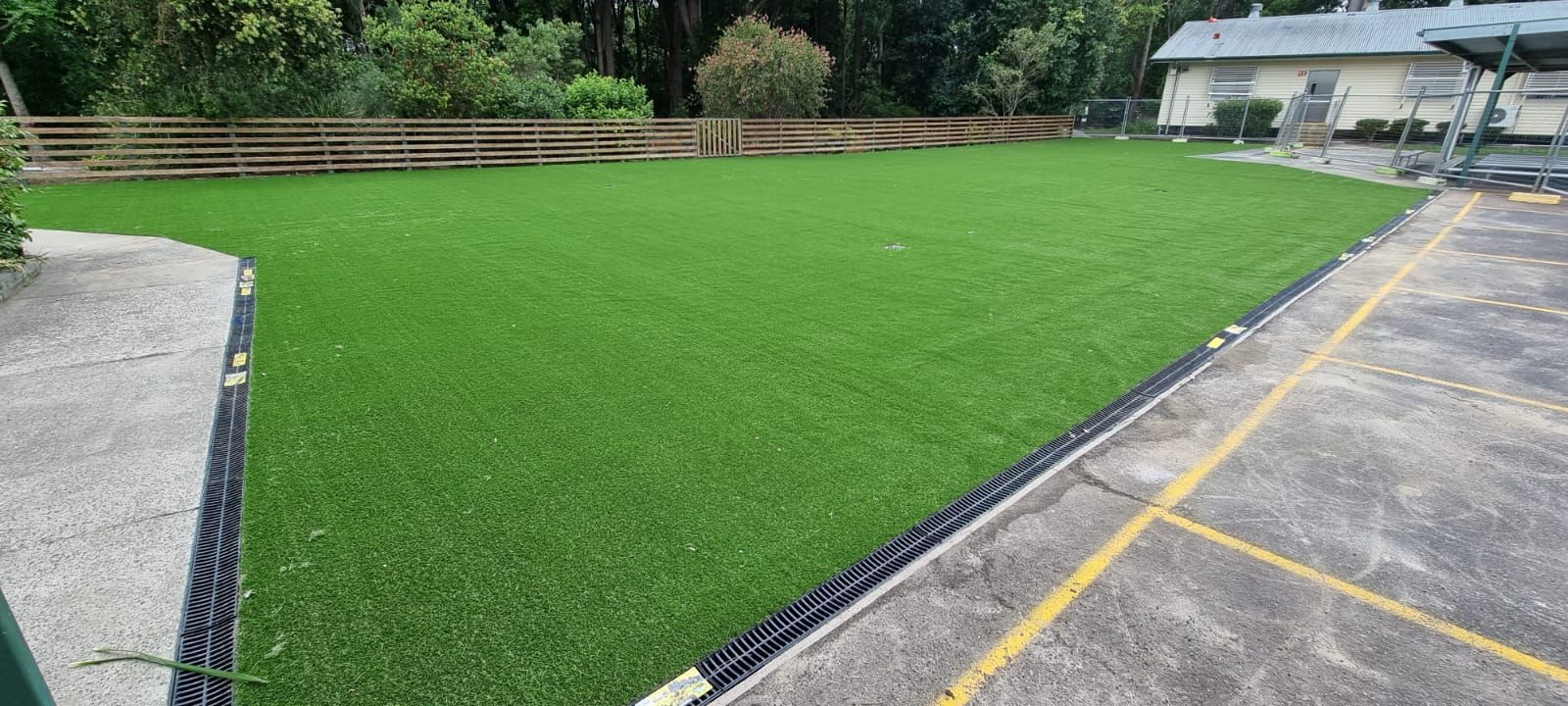 A large lawn with a fence in the background and a building in the background.