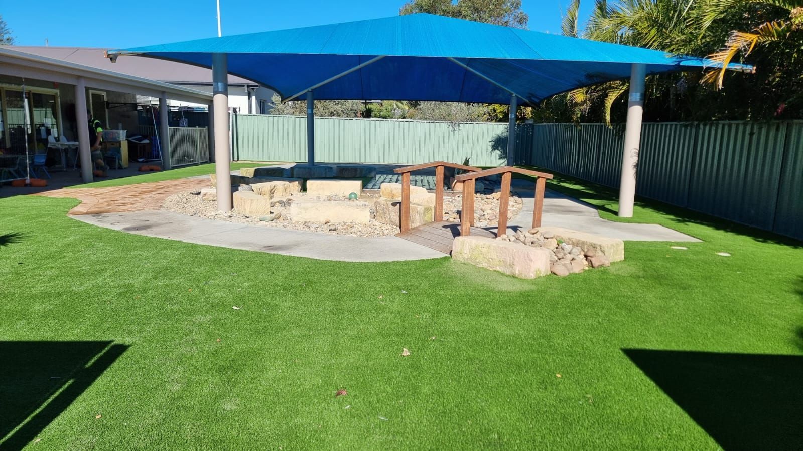 A blue umbrella is sitting on top of a lush green lawn.