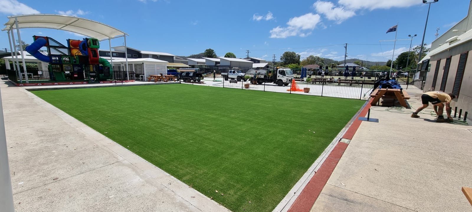 A large field of grass with a playground in the background.