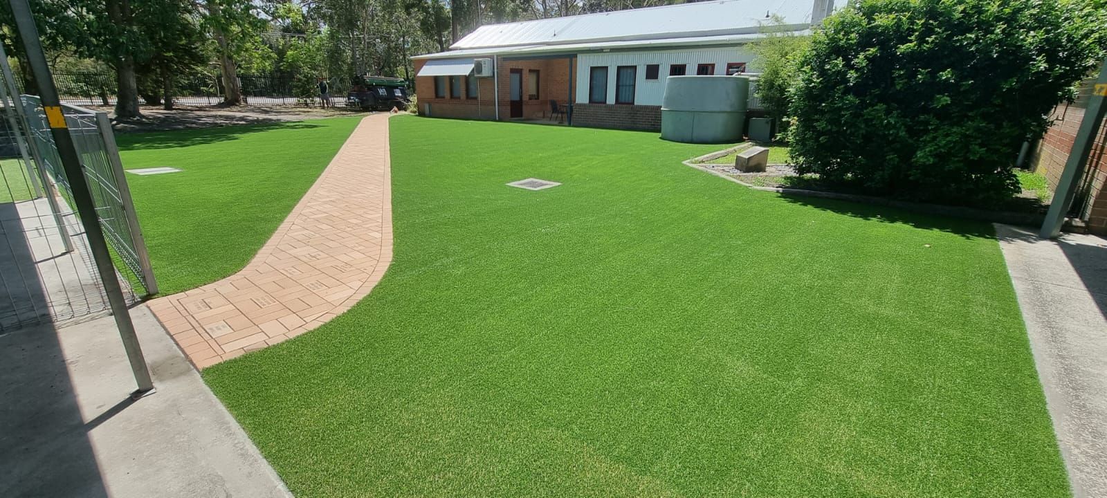 A lush green lawn with a brick walkway leading to a house.
