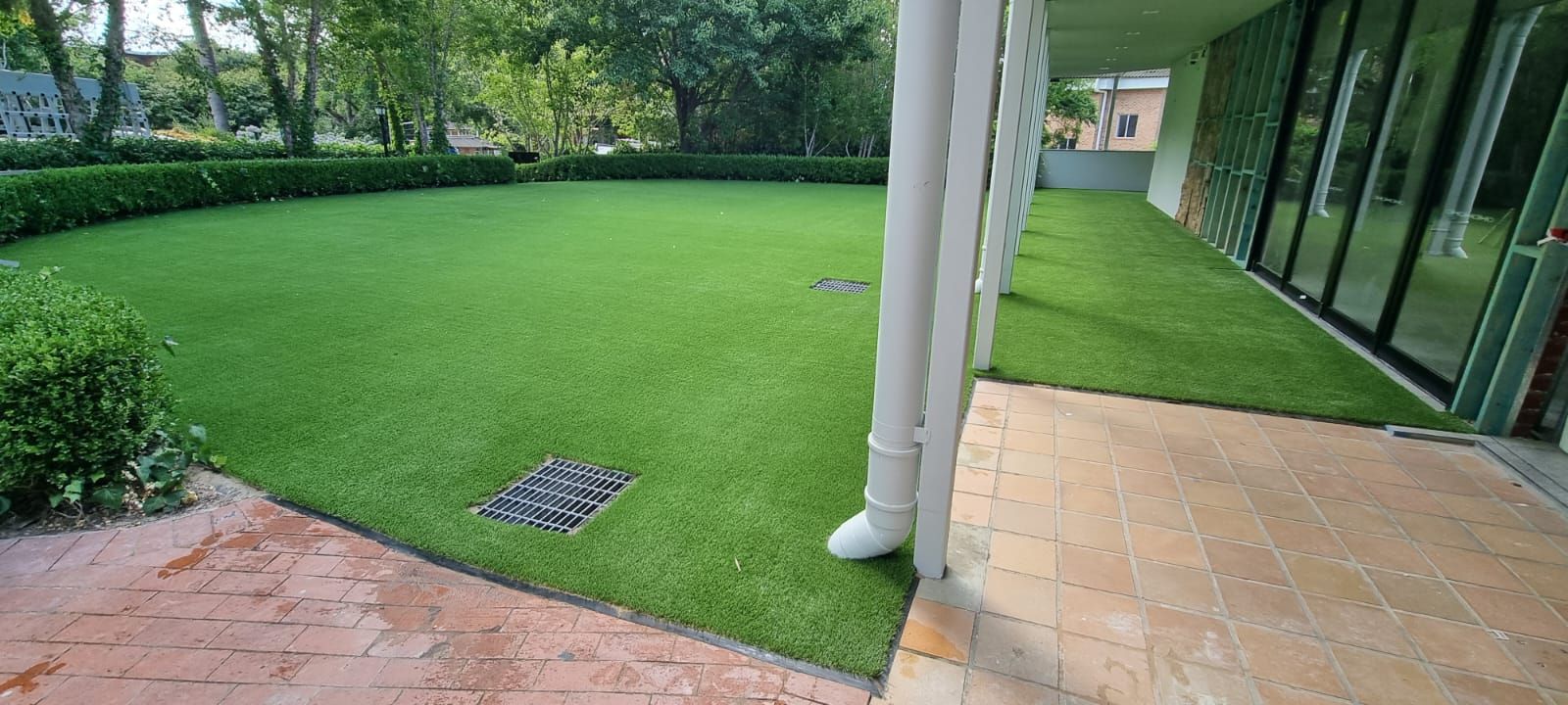 A large lawn with a drain pipe in the middle of it.