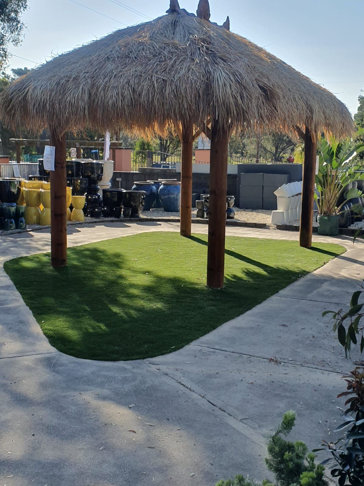 A thatched gazebo is sitting in the middle of a lush green field.