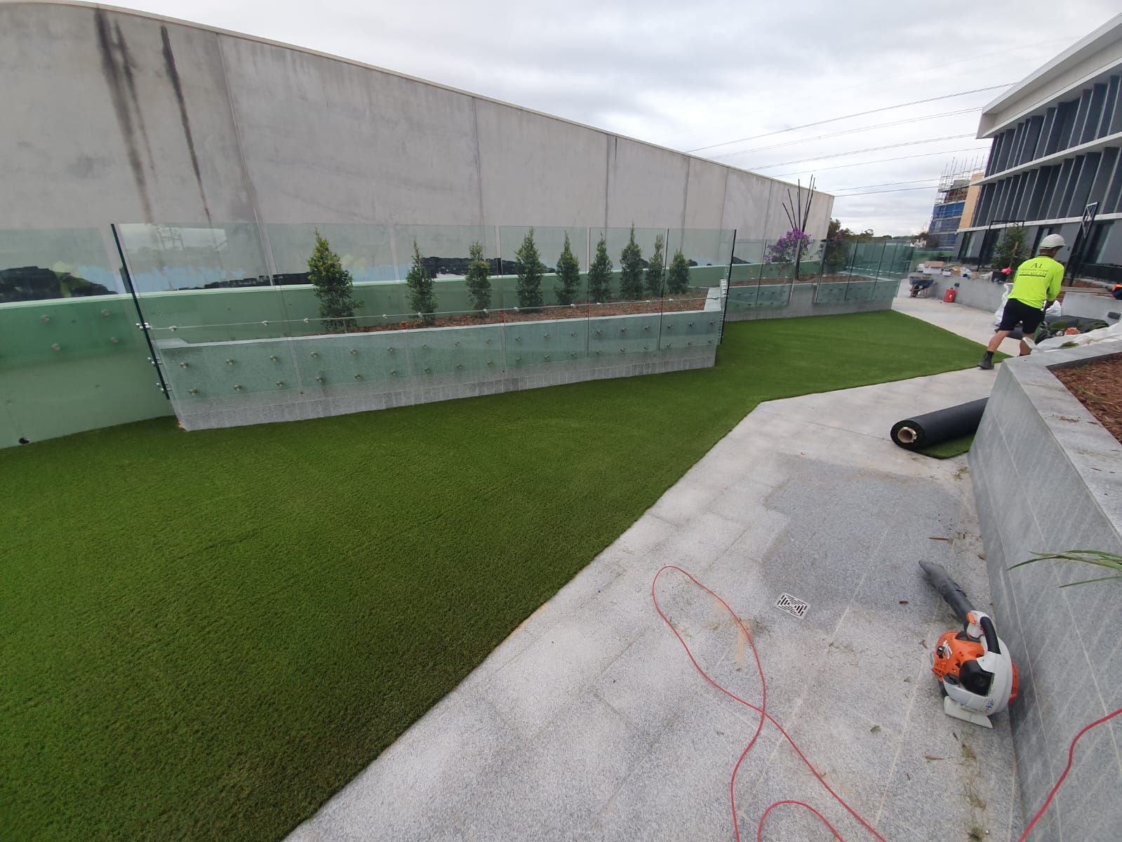 A man is laying artificial grass on the side of a building.