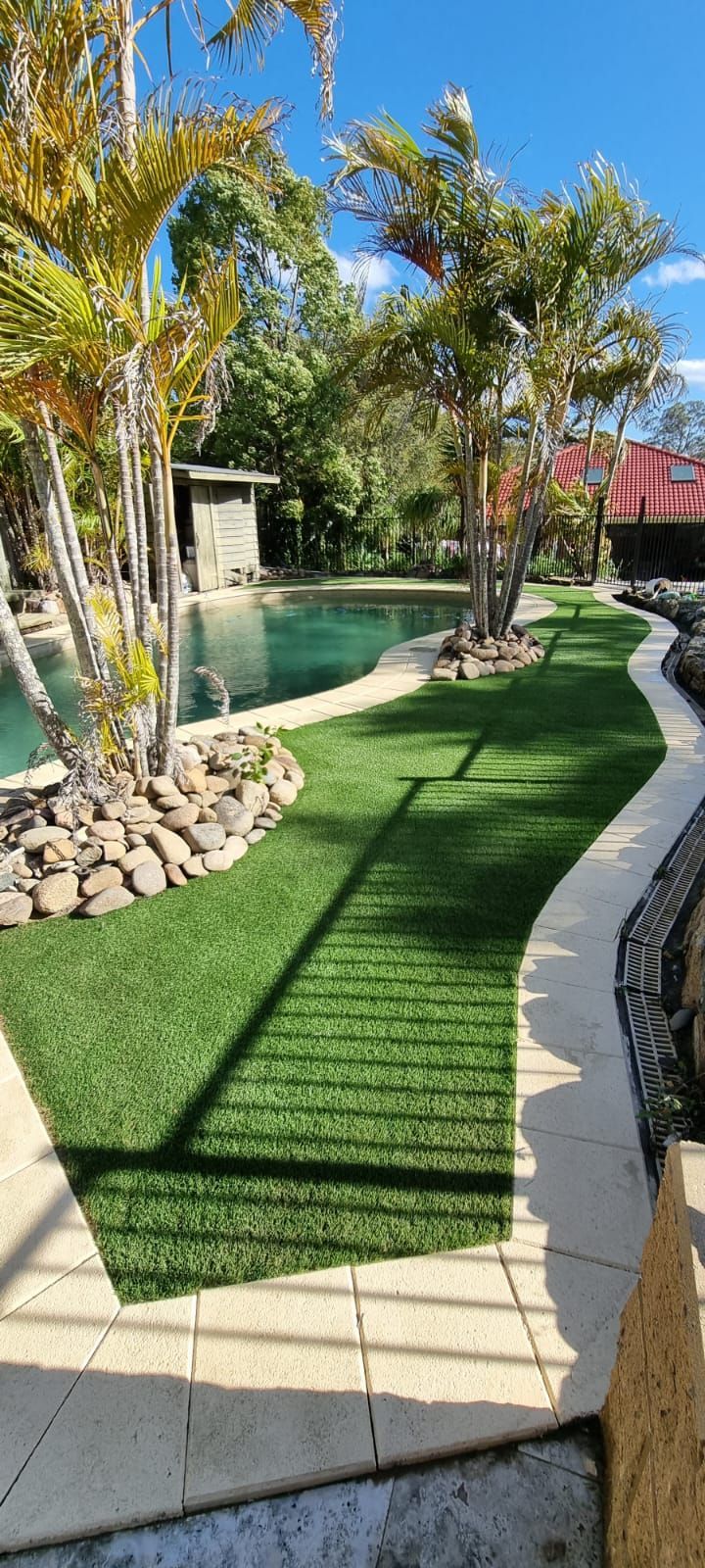 A lush green lawn with a swimming pool in the background.