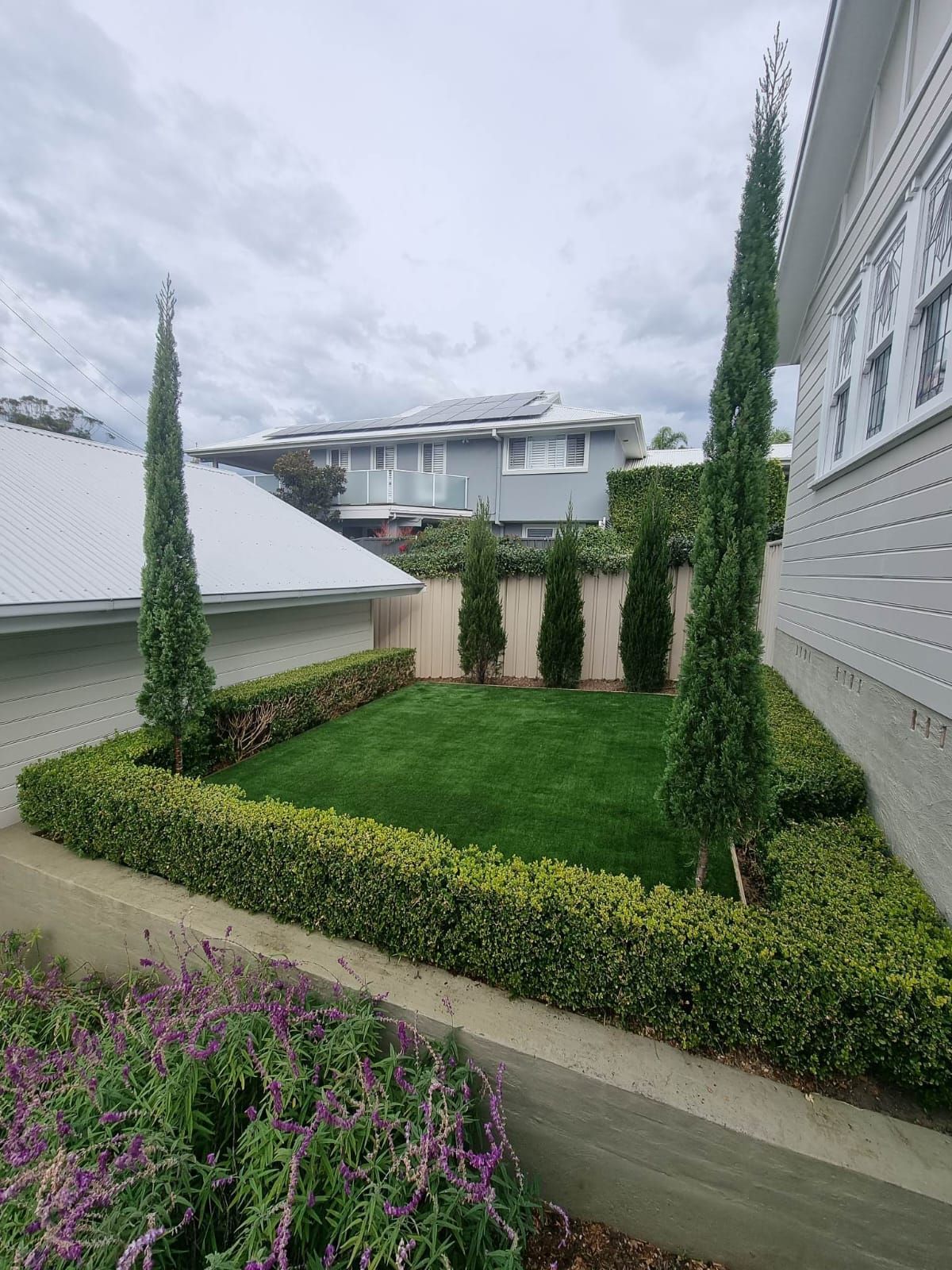 A lush green yard with trees and bushes in front of a house.