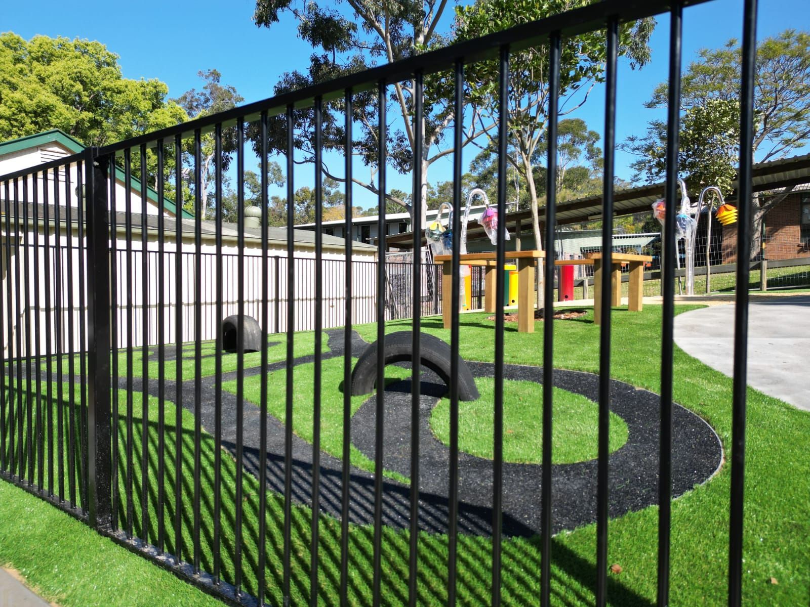 A black metal fence surrounds a playground in a park