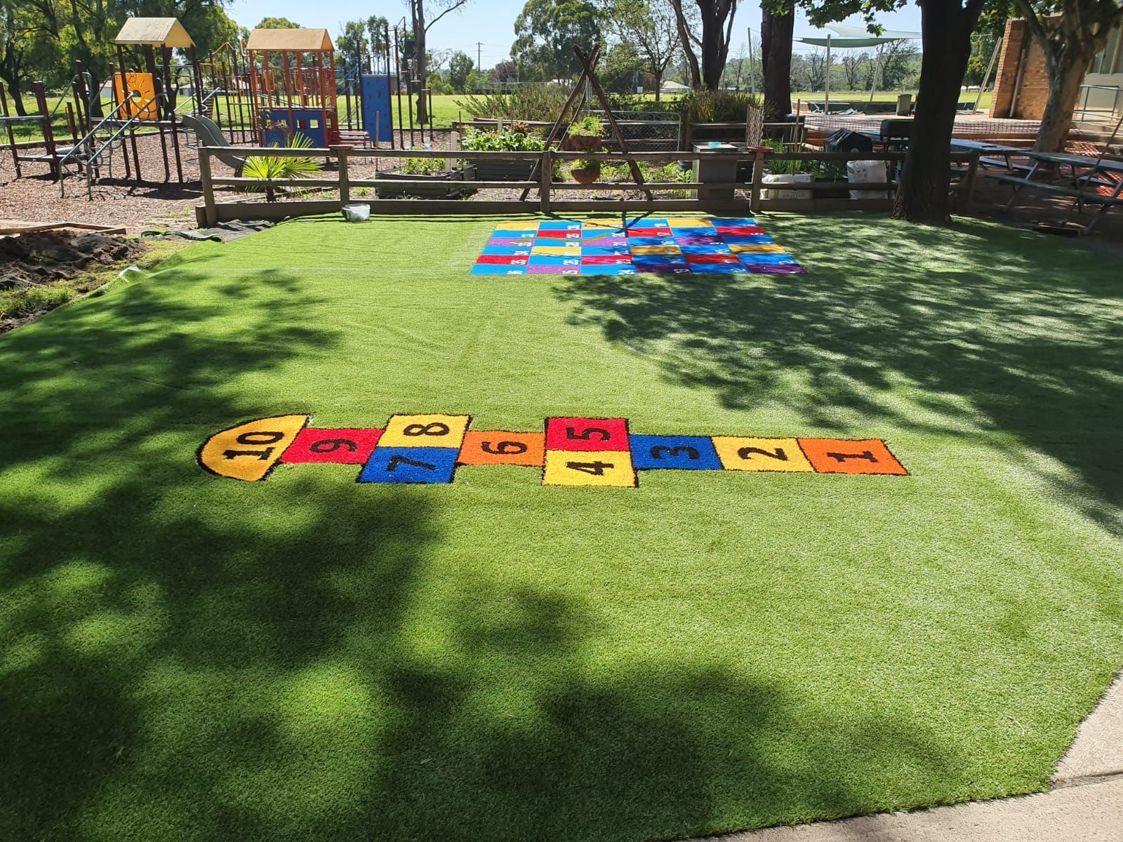 A hopscotch game is painted on the grass in a park.