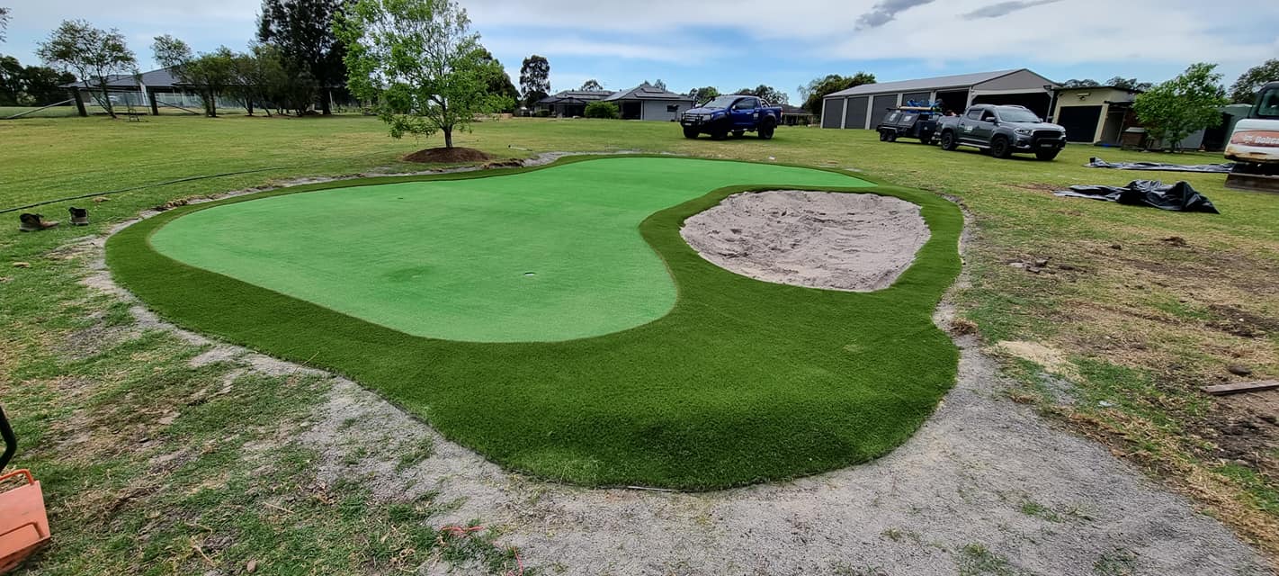 A small golf course is being built in the backyard of a house.