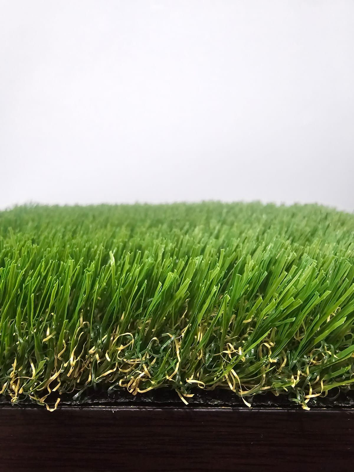 A close up of a piece of artificial grass on a white background.