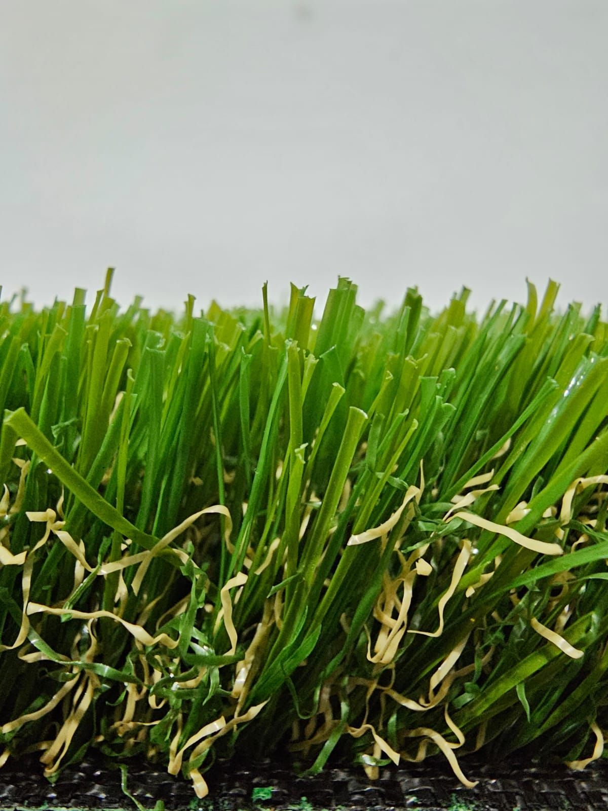 A lush green lawn with a wooden bench in the middle of it.