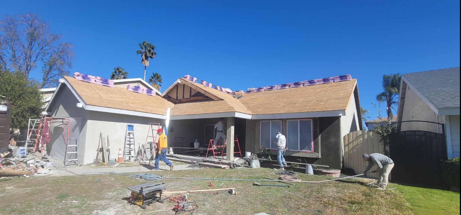 Construction workers repairing a house roof on a sunny day.