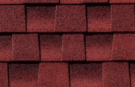 Close-up of red asphalt roof shingles, arranged in overlapping rows.