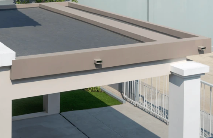 Beige flat roof of a carport with drain spouts, supported by white pillars.