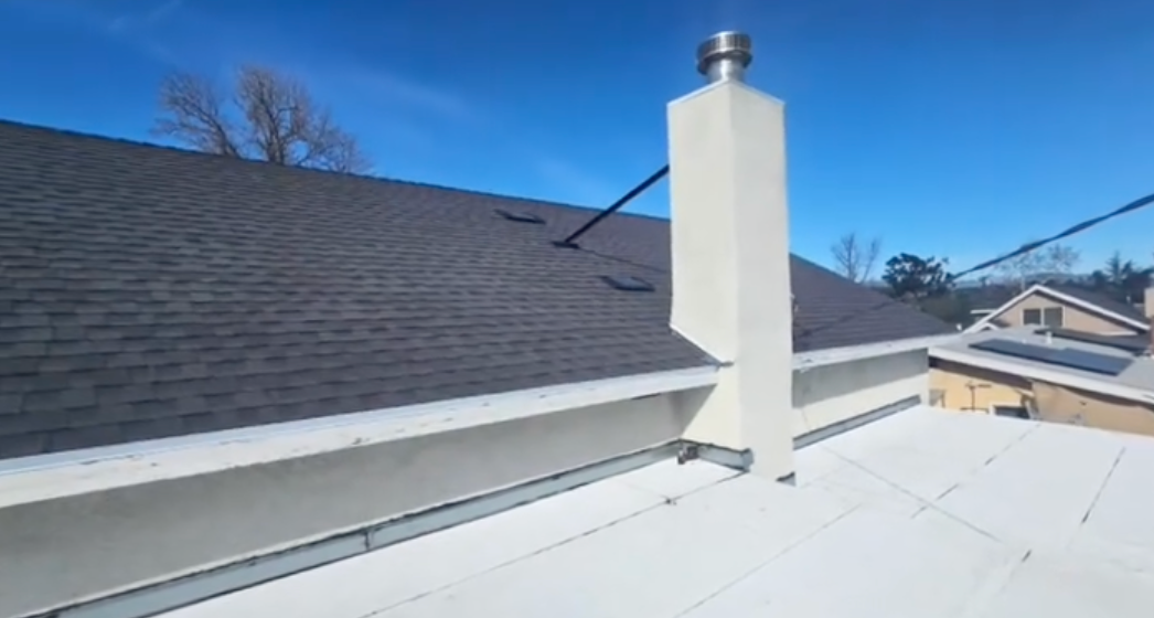 White roof vent chimney on a flat rooftop under a clear blue sky