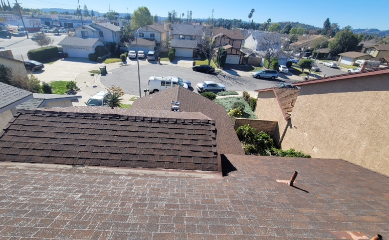 Rooftop view over suburban neighborhood with houses, parked cars, and a clear sky