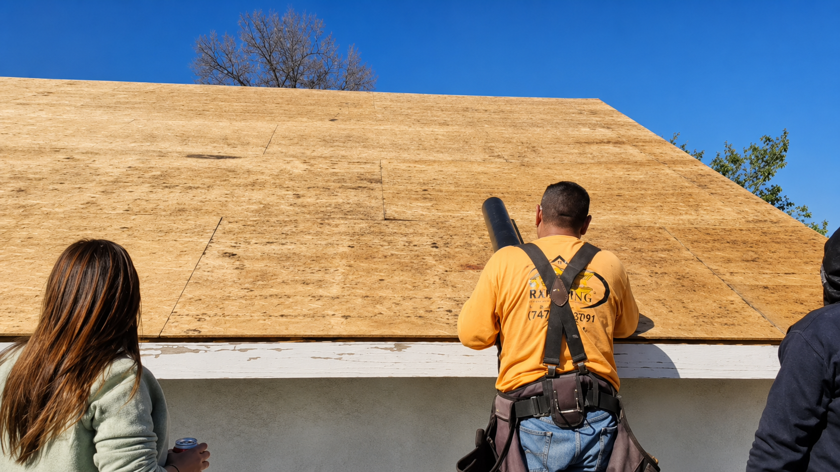 People examining a large wooden roof under construction, with two visible from behind.