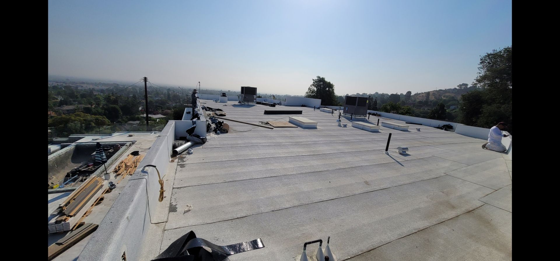 Rooftop with construction materials. City and sky in background.