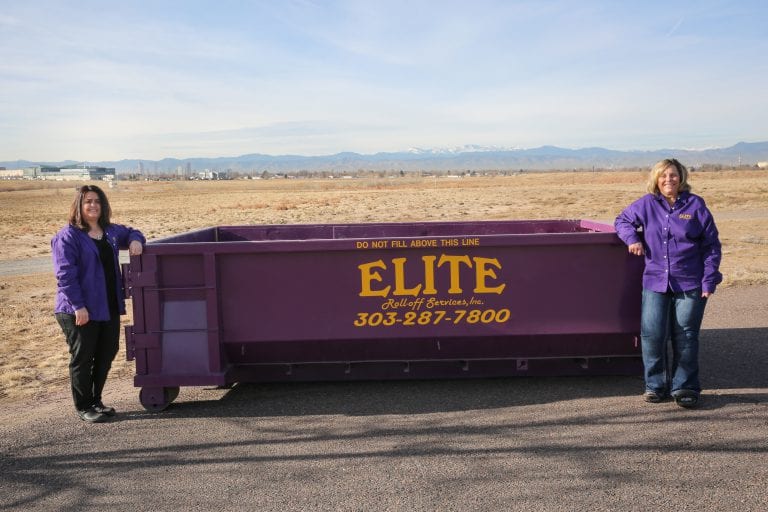 A large purple dumpster is in front of a house.