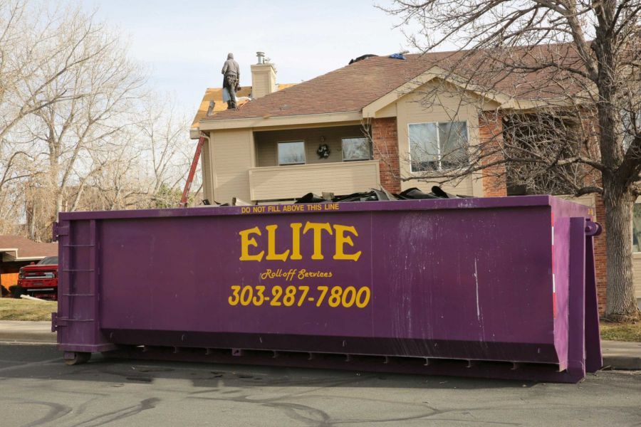 A large purple dumpster is in front of a house.