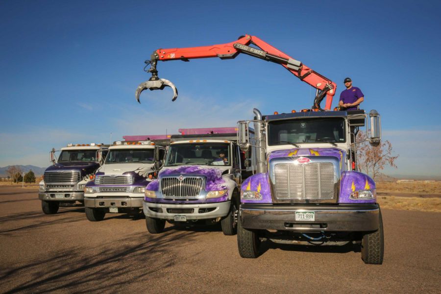 A man is standing on top of a truck with a crane attached to it.