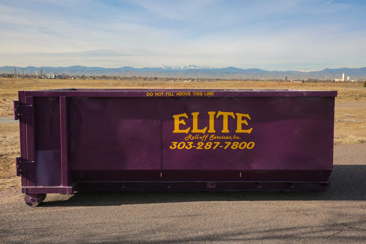 A large purple dumpster is parked on the side of the road.