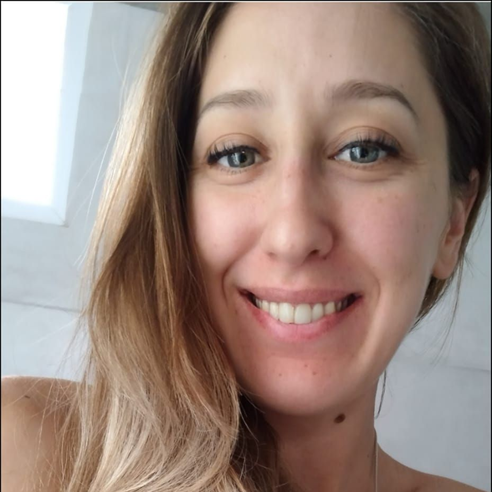 Mujer de cabello castaño claro, sonriendo, mirando directamente a la cámara.