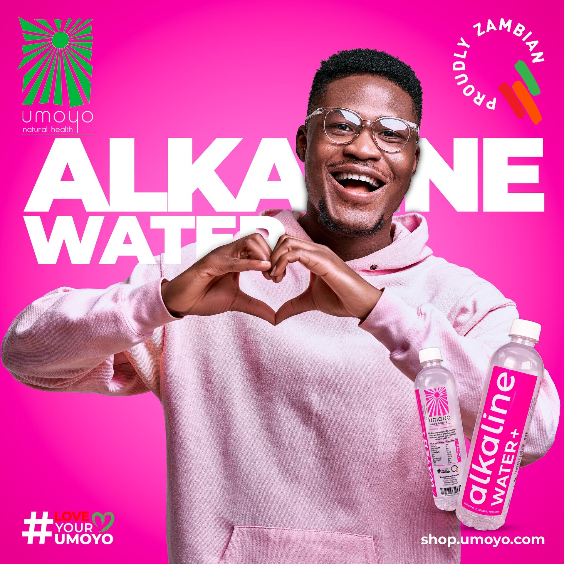 A man is making a heart shape with his hands while holding a bottle of alkaline water.