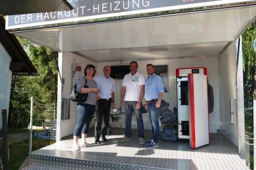 Eine Gruppe von Menschen steht unter einem Schild mit der Aufschrift „Der Haugut-Heizung“