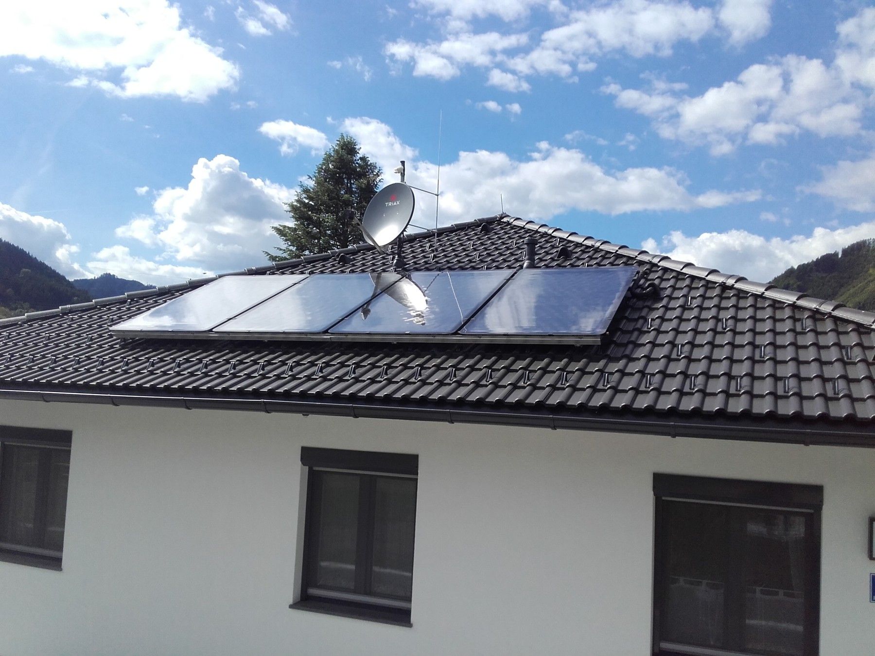 Ein Haus mit einer Solaranlage auf dem Dach und einer Satellitenschüssel