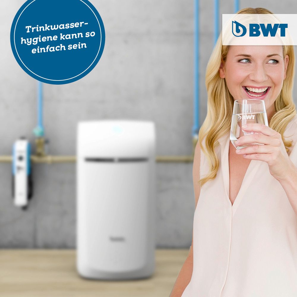 Eine Frau hält ein Glas Wasser vor einem BWT-Logo