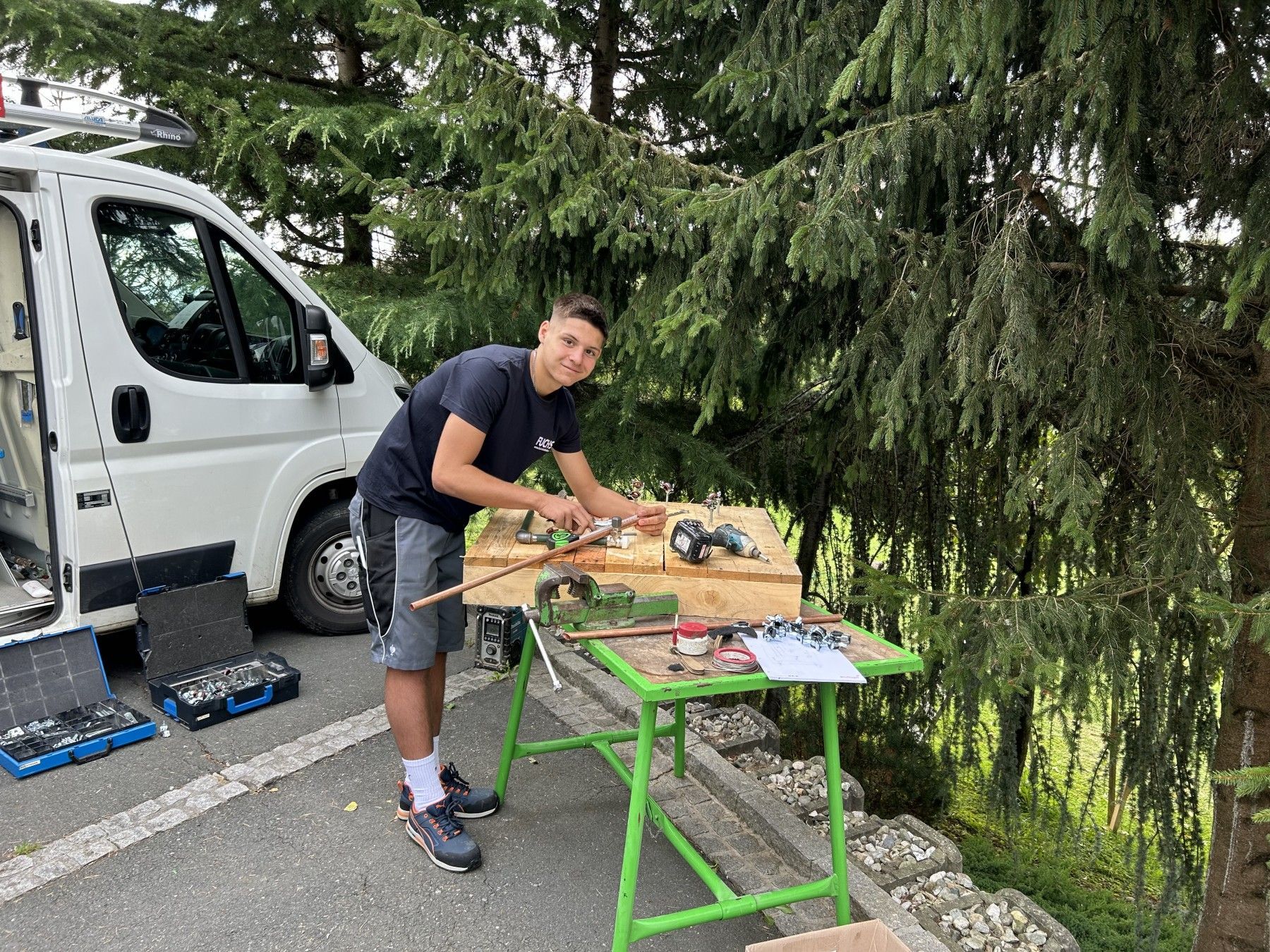 Ein Mann arbeitet an einem Tisch vor einem Lieferwagen.