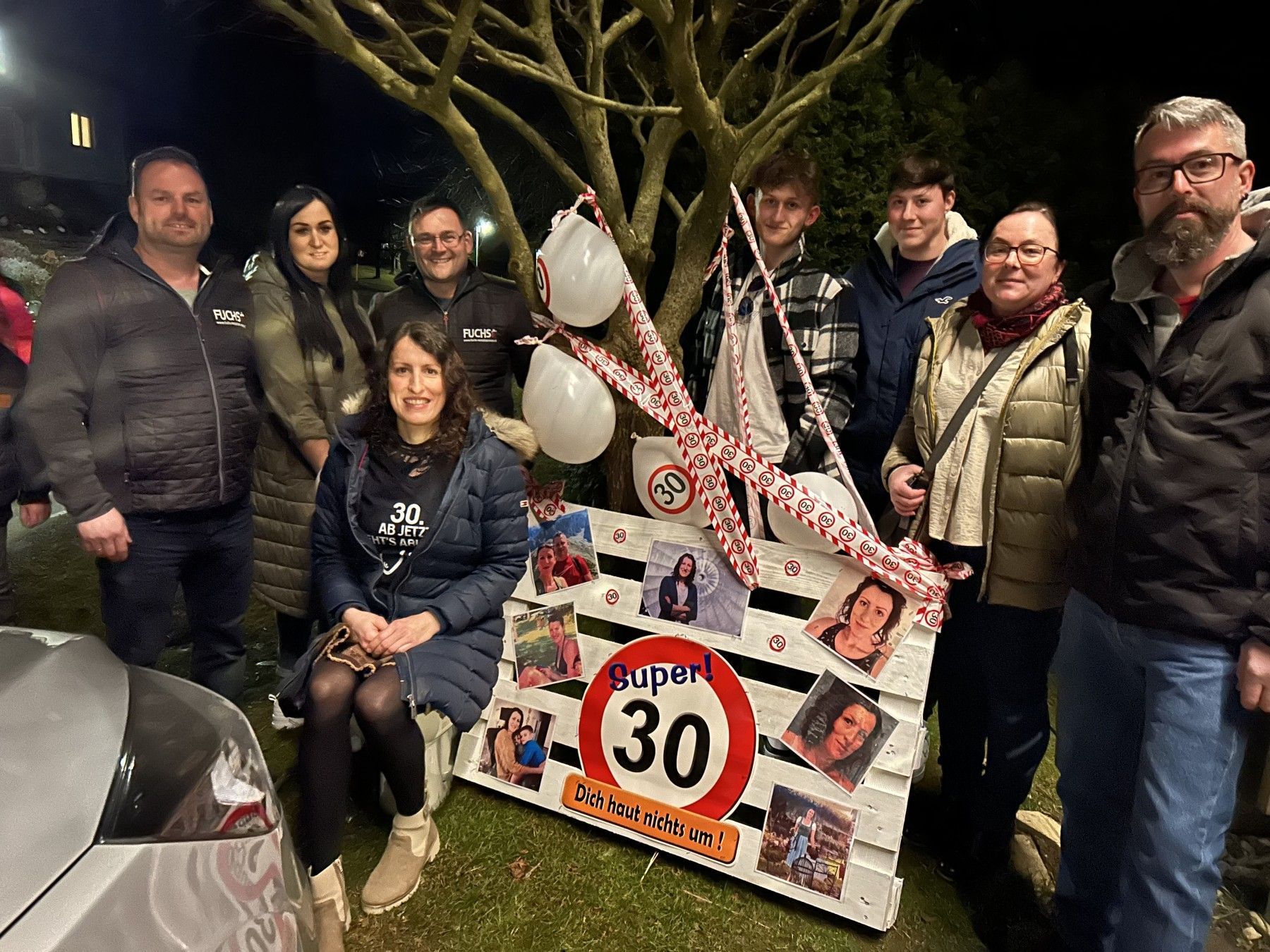 Eine Gruppe von Leuten steht um ein Schild herum, auf dem 30 steht.