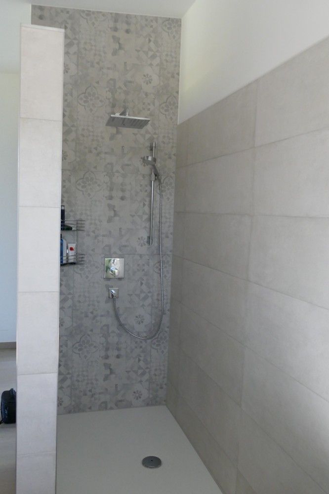 Ein Badezimmer mit ebenerdiger Dusche und Duschkopf.