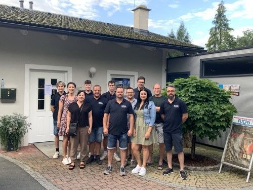 Eine Gruppe von Menschen posiert vor einem Gebäude für ein Foto.