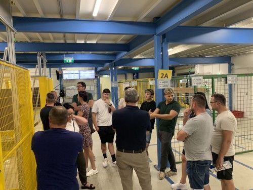 Eine Gruppe von Leuten steht in einem Lagerhaus und unterhält sich.