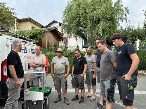Eine Gruppe Männer steht vor einem weißen Lieferwagen.