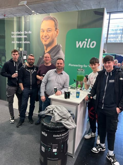 Eine Gruppe von Männern steht vor einem Wilo-Schild