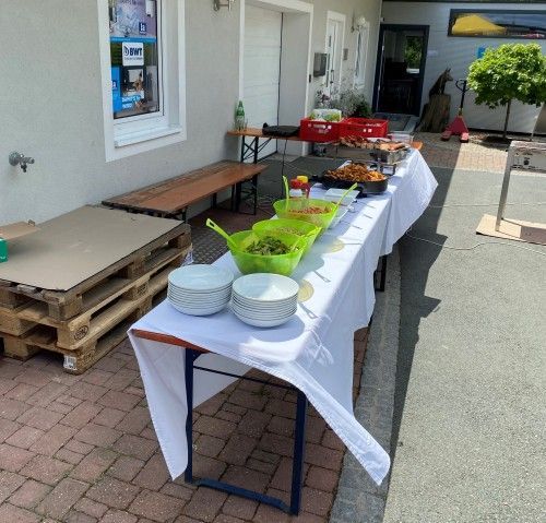 Ein Tisch mit Schüsseln voller Essen darauf vor einem Gebäude