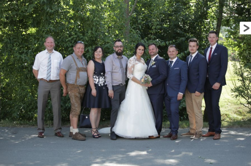 Eine Braut und ein Bräutigam posieren mit ihrer Hochzeitsgesellschaft für ein Foto.