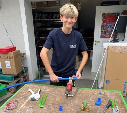 Ein junger Mann in einem blauen Hemd arbeitet an einem Rohr
