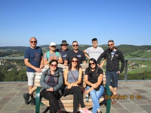 Eine Gruppe von Menschen posiert auf einer Bank sitzend für ein Foto.