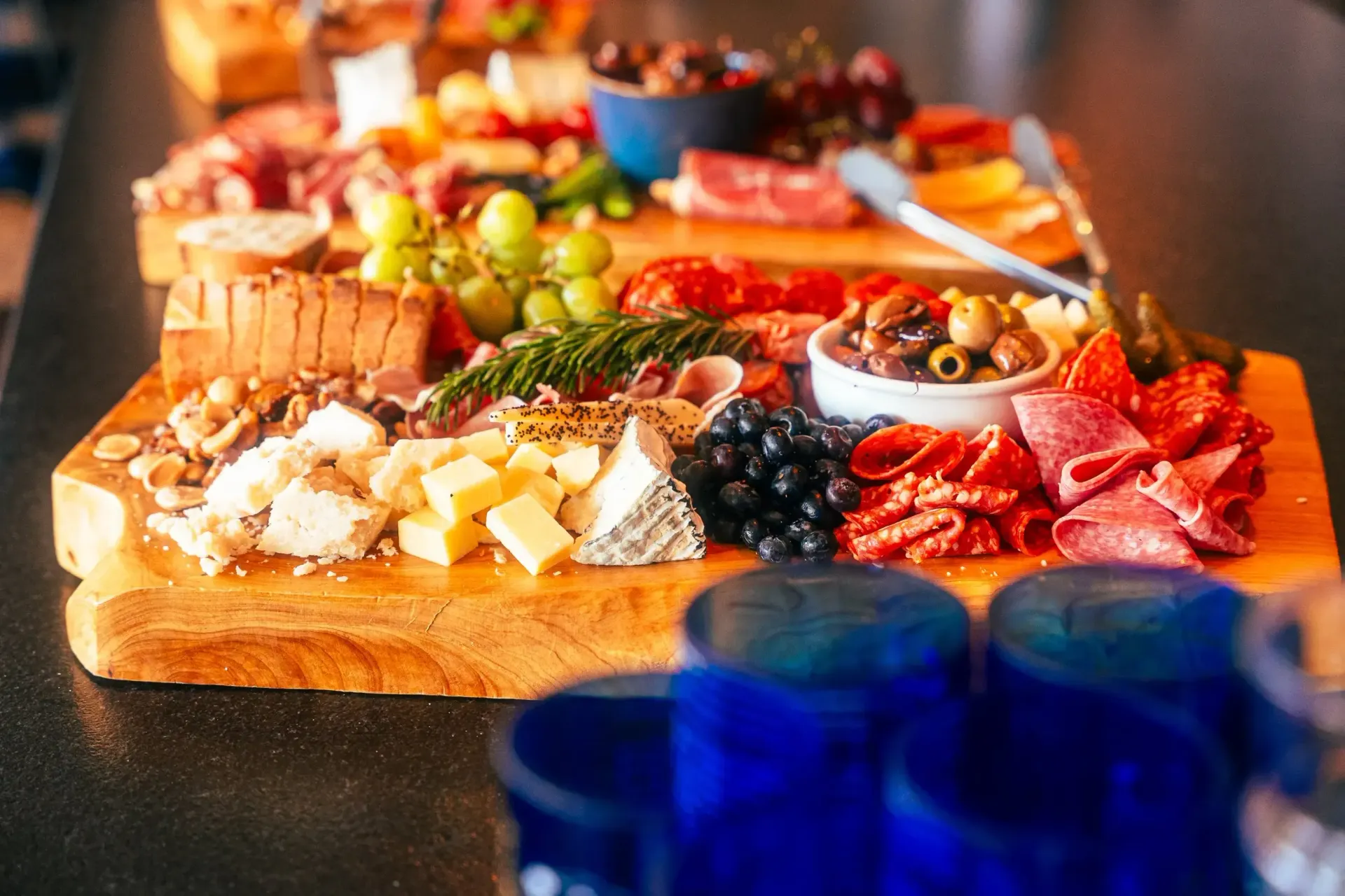 Charcuterie board with meats, cheeses, grapes, olives, and nuts on wooden planks.