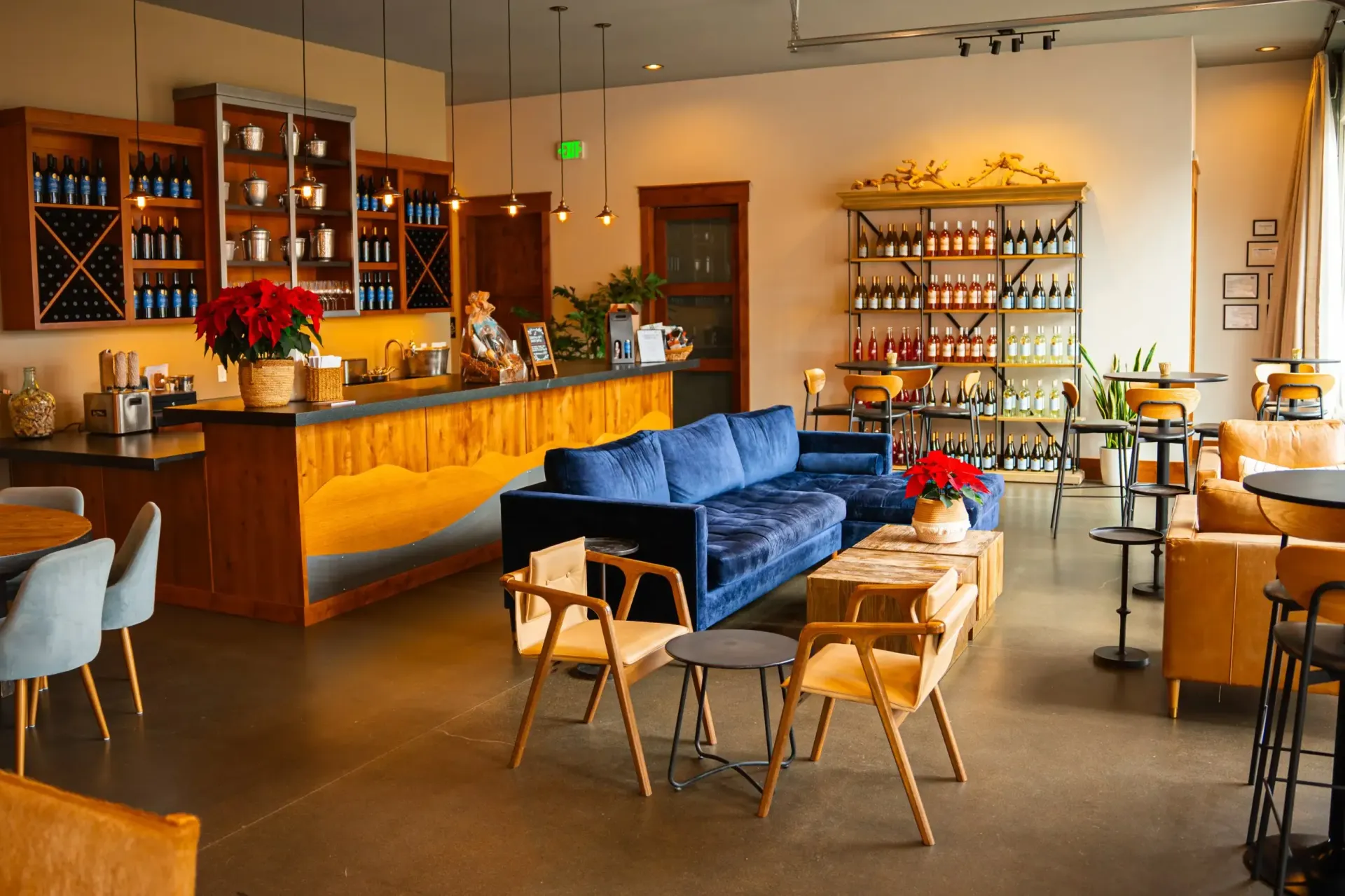 Wine tasting room with a bar, seating areas, and shelves stocked with bottles.