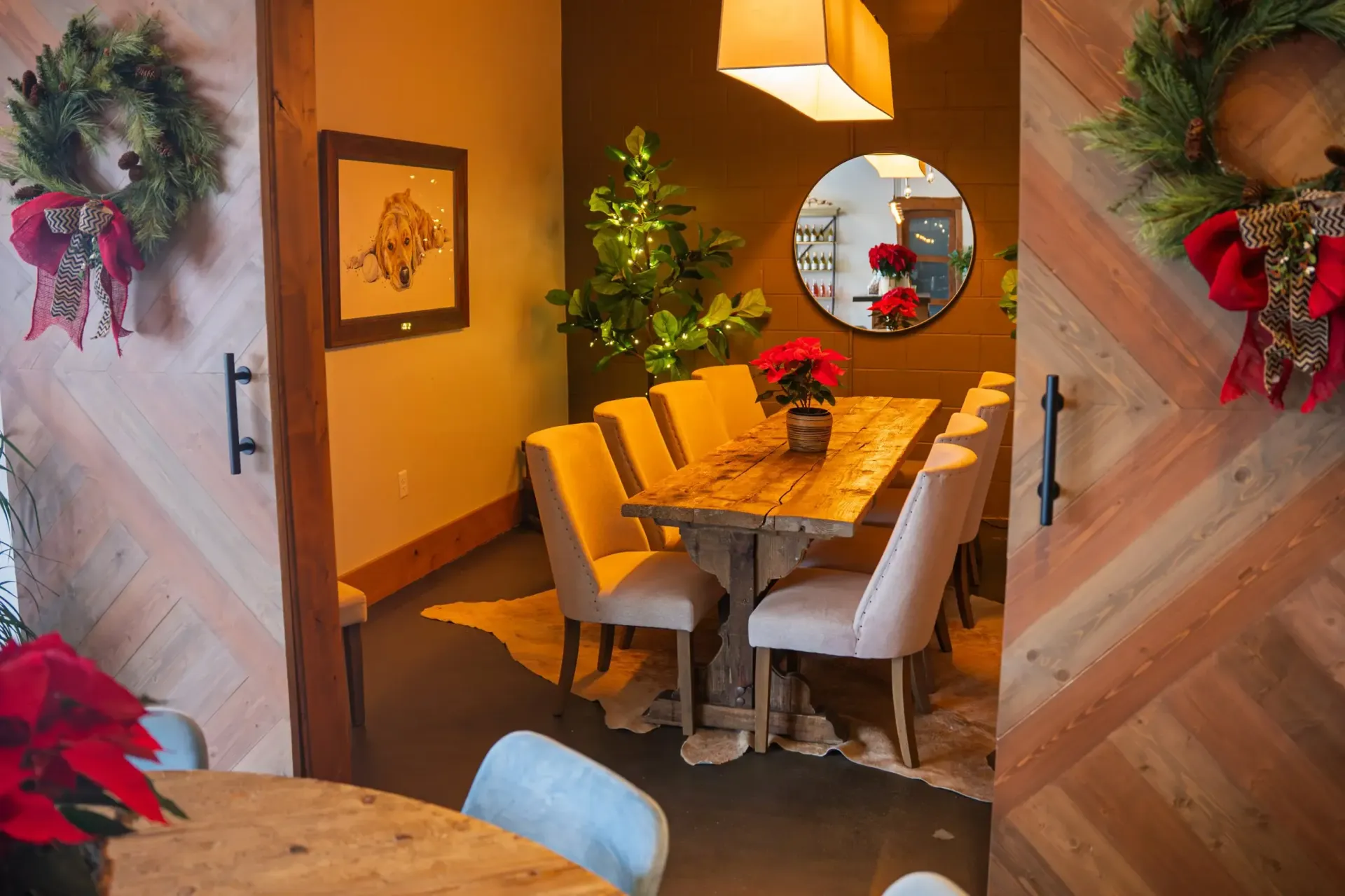 Dining room with wooden table, upholstered chairs, and Christmas decorations.