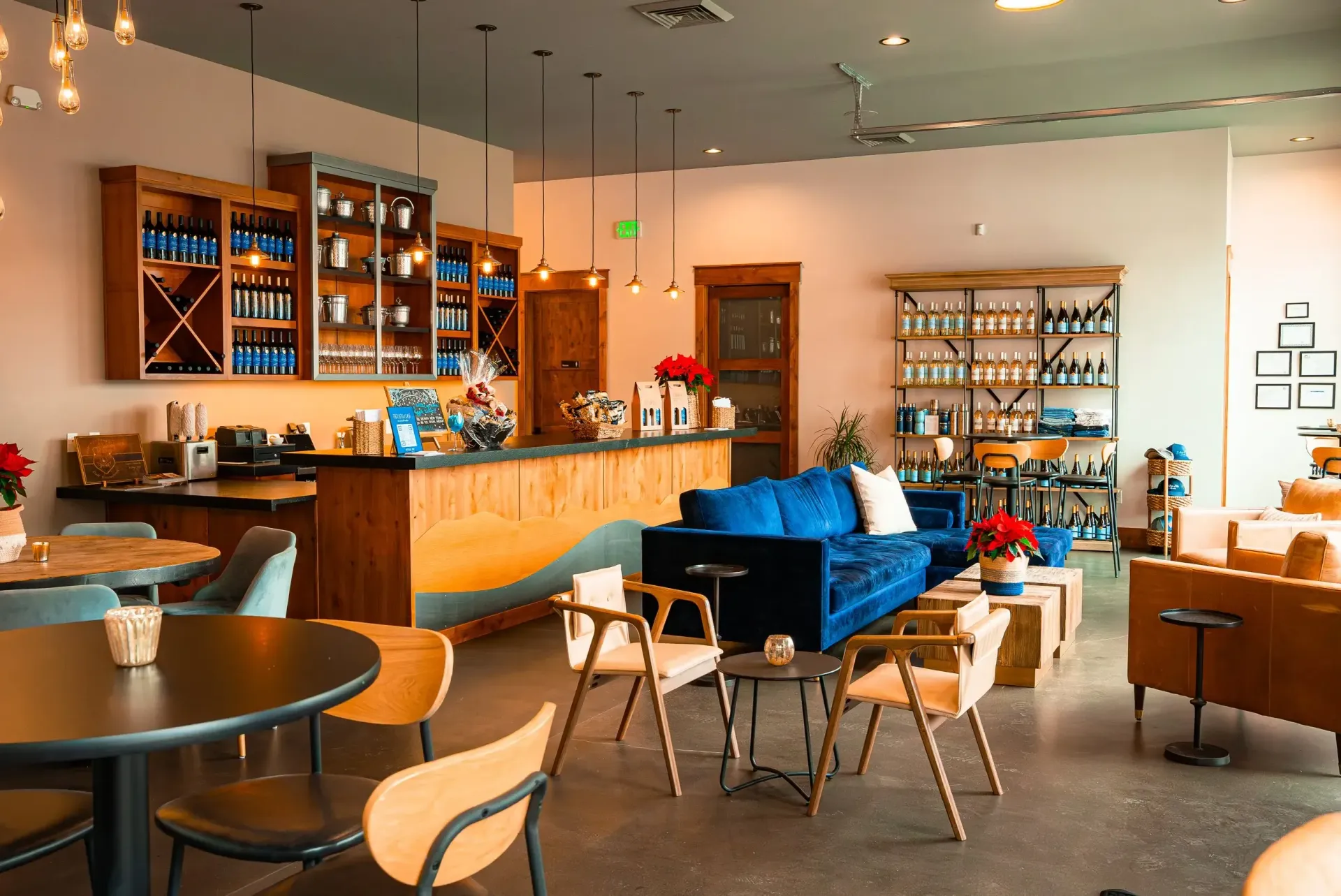 Interior view of a cafe with tables, chairs, bar, and shelves displaying merchandise. Blue and wood tones dominate.