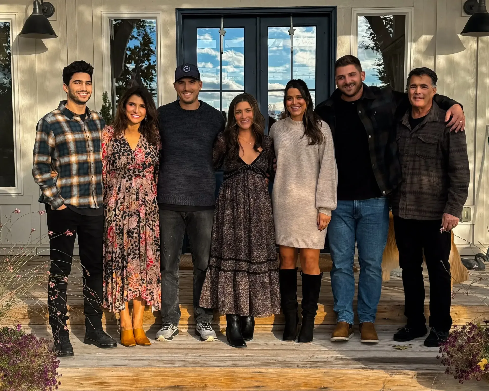 Group of seven people smiling in front of a house. Confetti in the air.