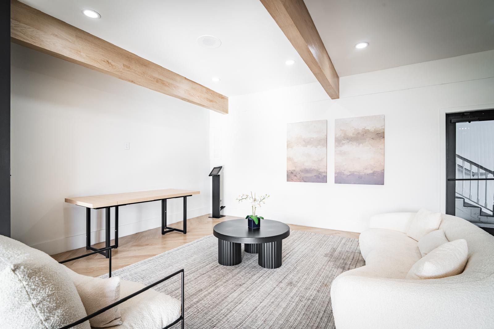 A living room with a couch , chair , table and paintings on the wall.