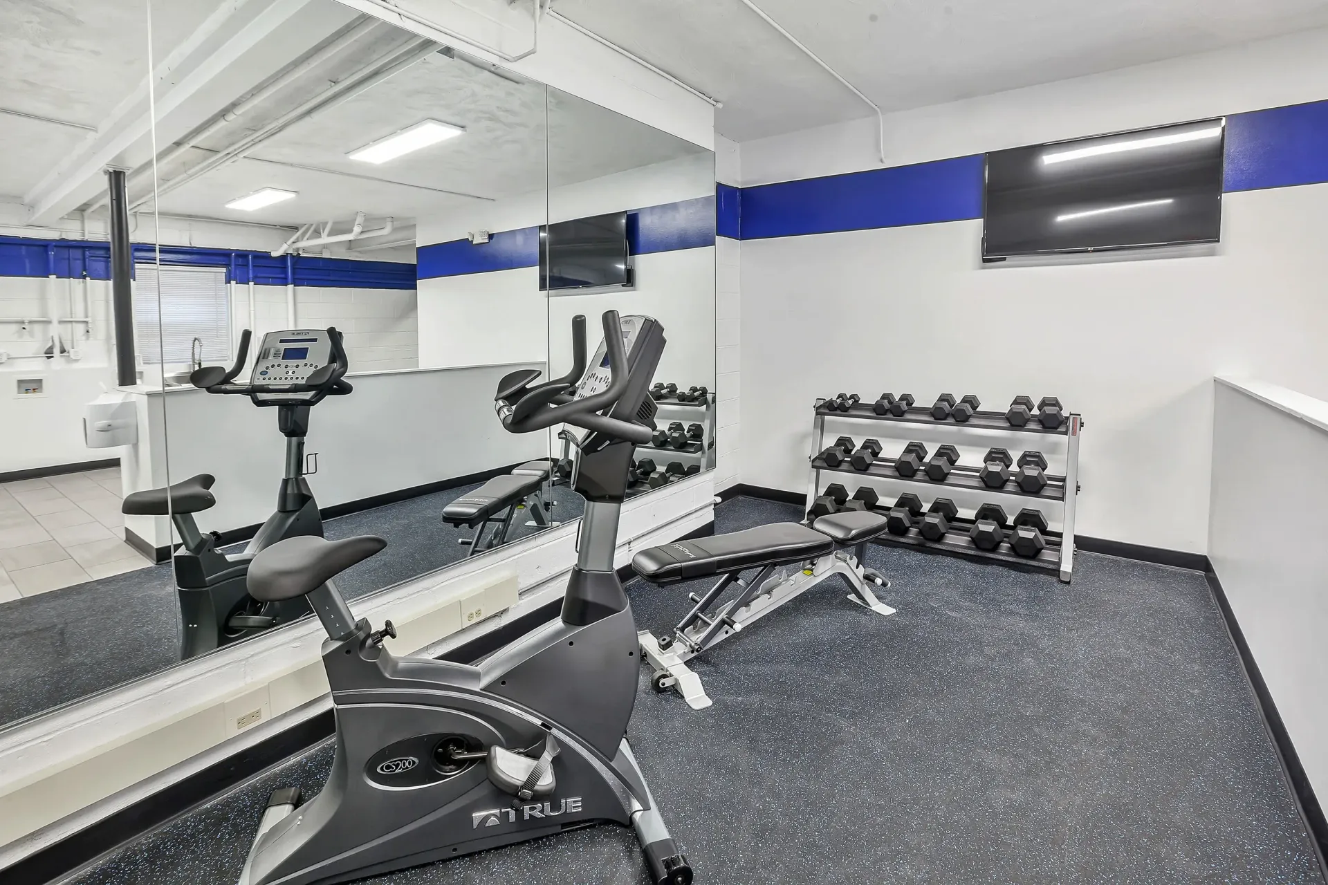 Fitness room with a stationary bike, treadmill, and a rack of dumbbells beside a large mirror. 
Ready to make Joralemon your home? Contact us today to learn more about our pet-friendly 1, 2, and 3-bedroom apartments for rent in Belleville, NJ. We can’t wait to welcome you home!