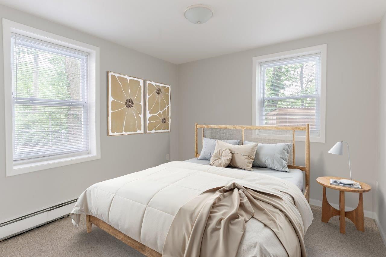 Minimal bedroom with white bed, tan decor, two windows, and a small side table lamp