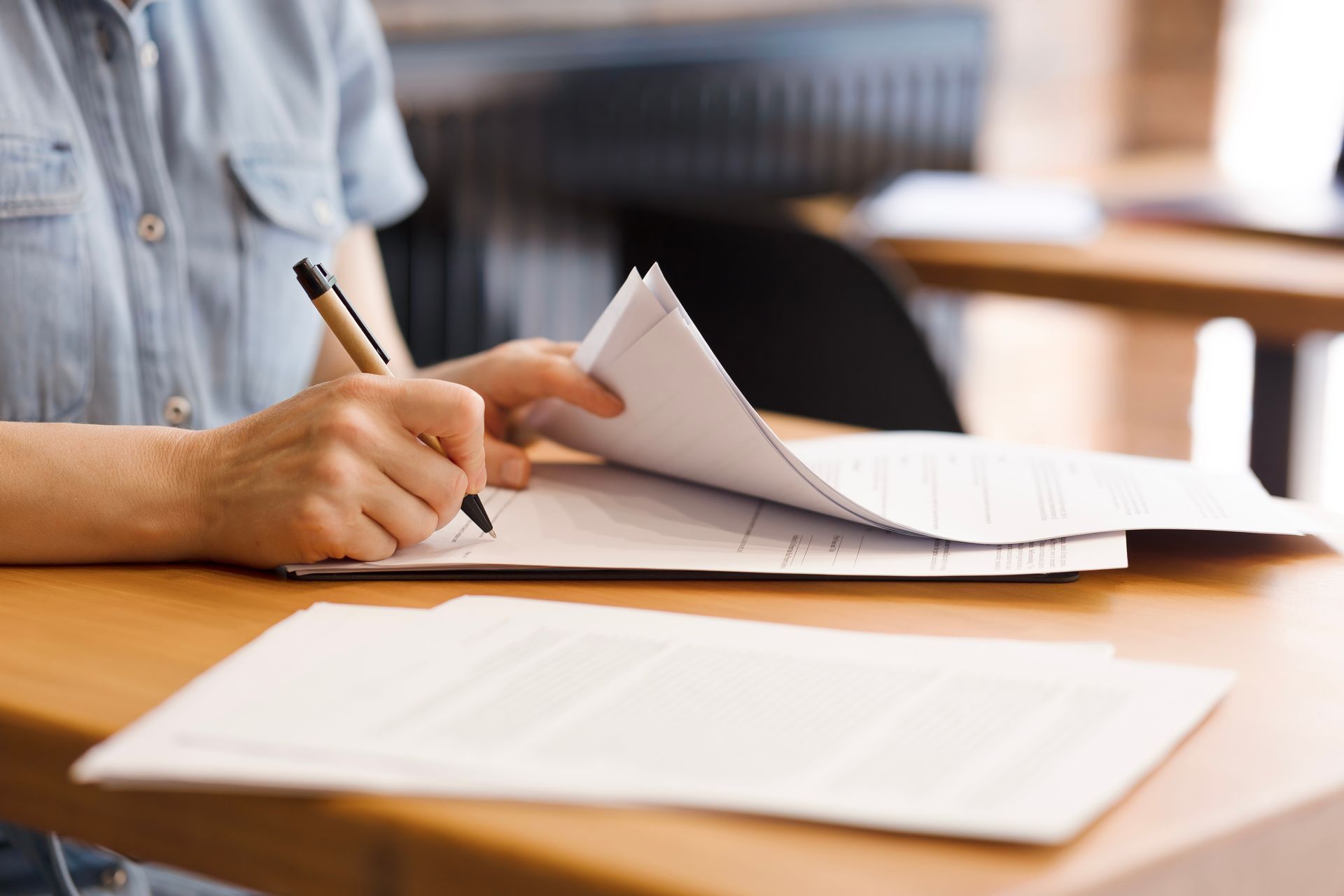 A person is sitting at a desk signing a document.